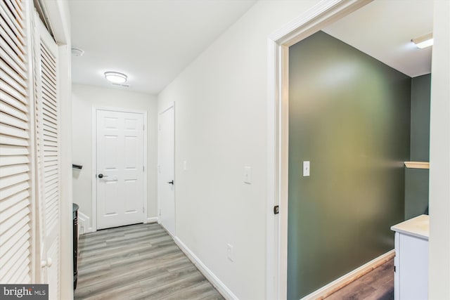 corridor with light wood-style flooring and baseboards