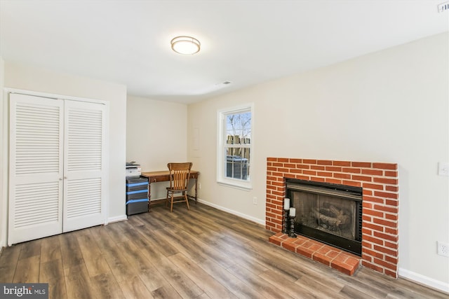 office area featuring a brick fireplace, baseboards, and wood finished floors