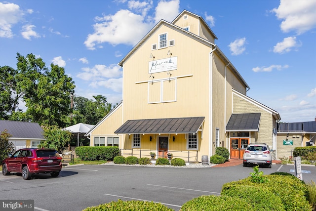 view of front of house featuring a standing seam roof, uncovered parking, metal roof, and covered porch