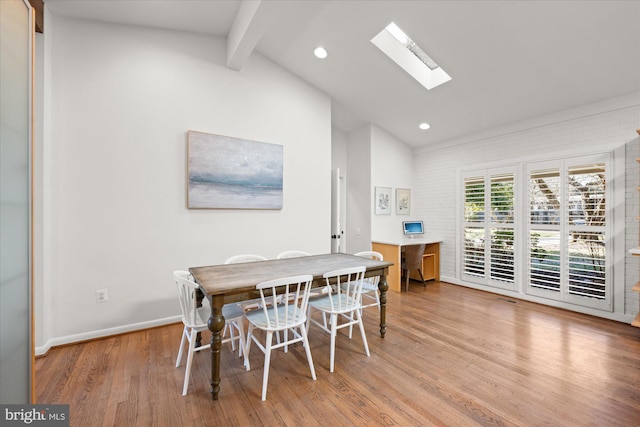 dining room featuring vaulted ceiling with skylight, recessed lighting, wood finished floors, and baseboards