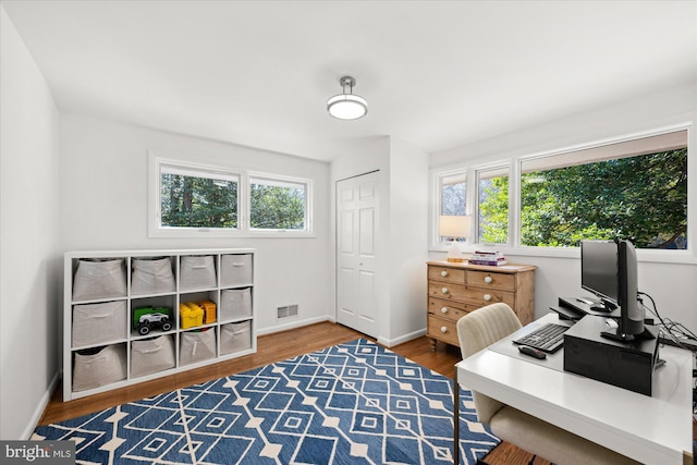 office space with a healthy amount of sunlight, visible vents, baseboards, and wood finished floors