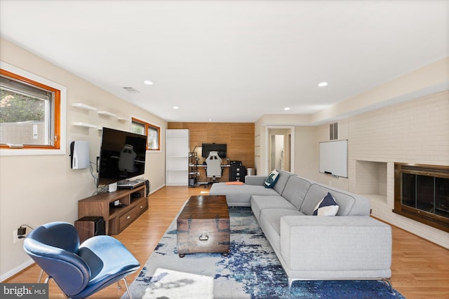 living area featuring baseboards, a fireplace, visible vents, and wood finished floors