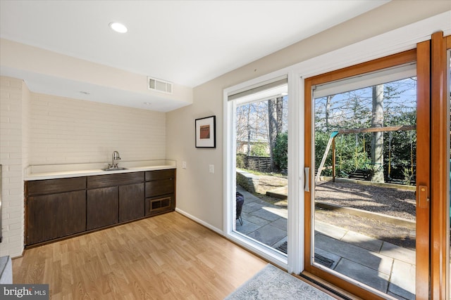 doorway featuring light wood finished floors, baseboards, visible vents, and a sink