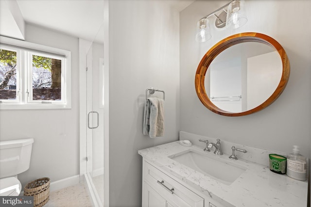 bathroom featuring a stall shower, vanity, toilet, and baseboards