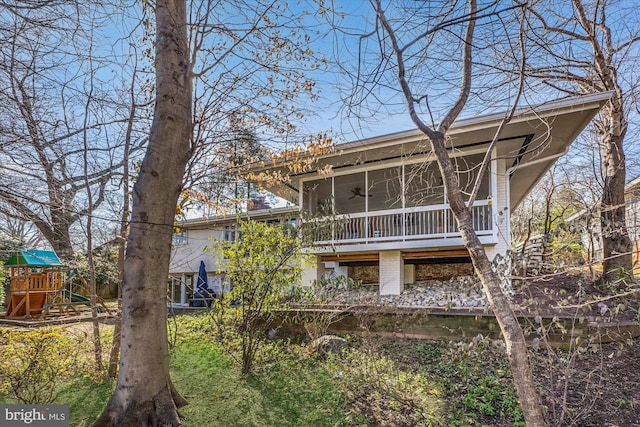 rear view of property featuring a sunroom and a playground