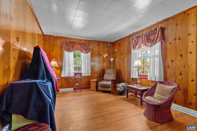 living area featuring wooden walls, baseboards, and wood finished floors