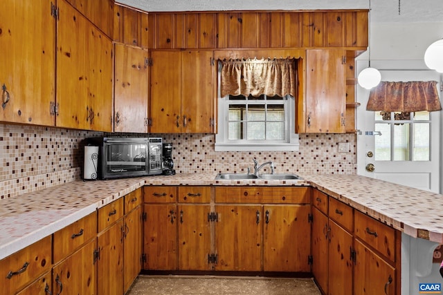 kitchen featuring tasteful backsplash, a wealth of natural light, light countertops, and a sink