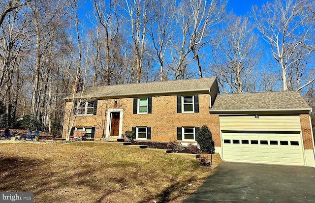 raised ranch with an attached garage, roof with shingles, aphalt driveway, and brick siding