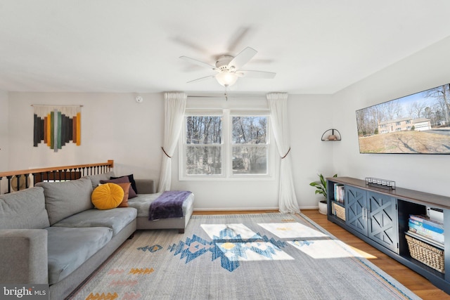 living room with a ceiling fan, baseboards, and wood finished floors