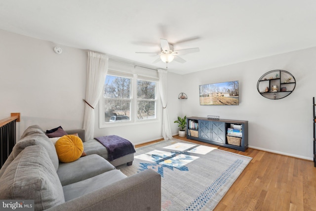 living room with a ceiling fan, baseboards, and wood finished floors