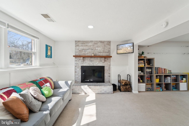 living area with carpet floors, a fireplace, visible vents, and wainscoting