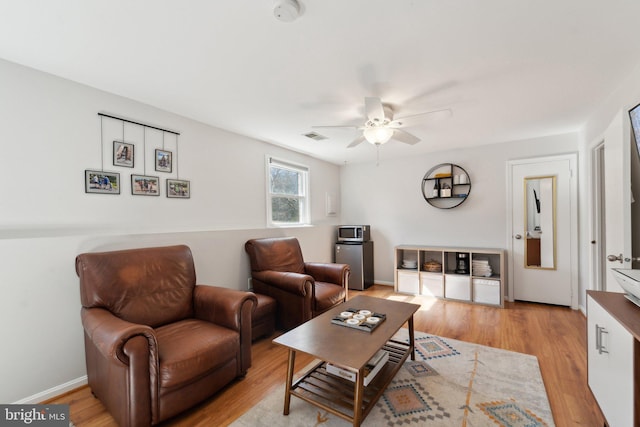 living room featuring ceiling fan, baseboards, visible vents, and light wood-style floors