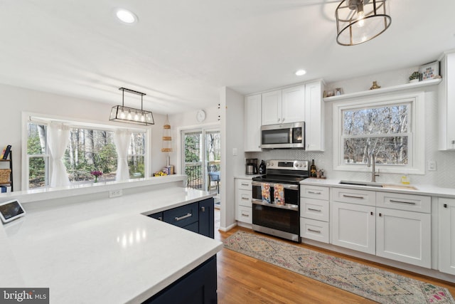 kitchen with tasteful backsplash, light countertops, appliances with stainless steel finishes, white cabinets, and a sink