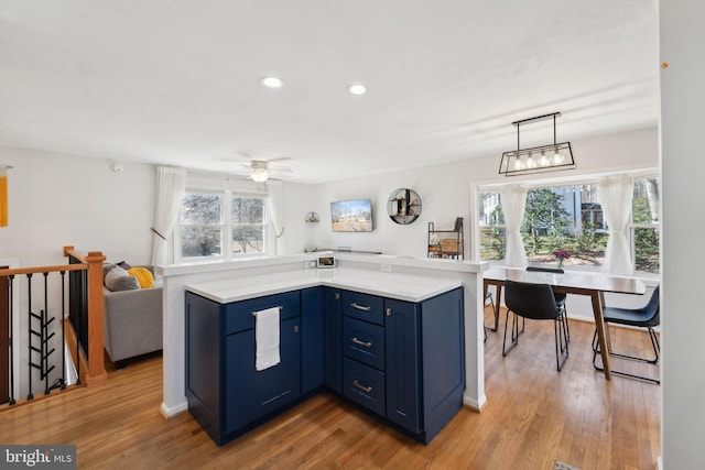 kitchen featuring light countertops, blue cabinetry, plenty of natural light, and wood finished floors