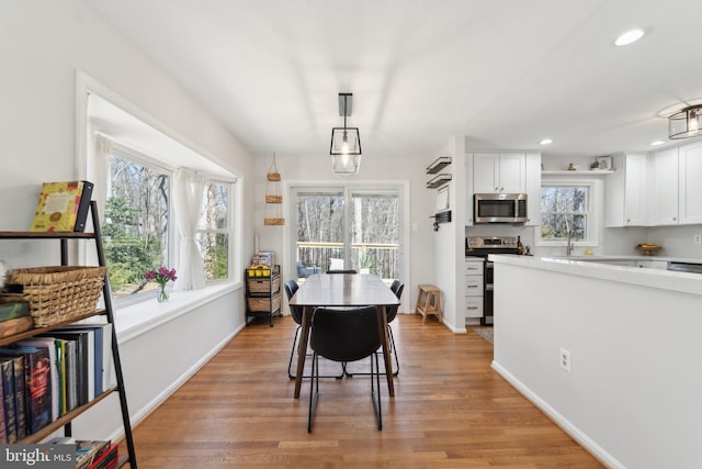 dining space featuring light wood finished floors, baseboards, and recessed lighting