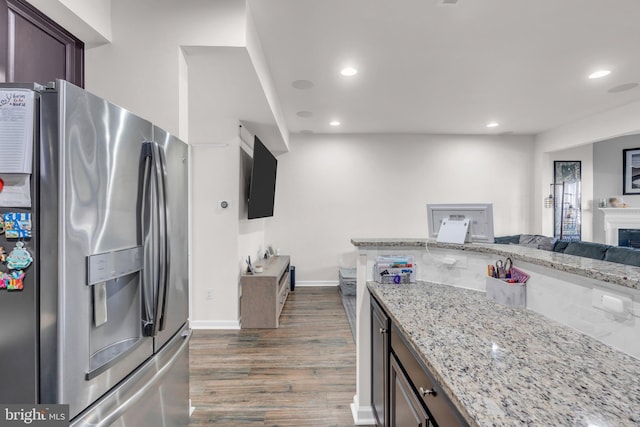 kitchen with stainless steel fridge, dark wood finished floors, light stone counters, dark brown cabinets, and recessed lighting