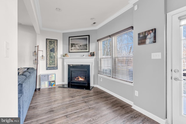 living room featuring baseboards, visible vents, a glass covered fireplace, wood finished floors, and crown molding