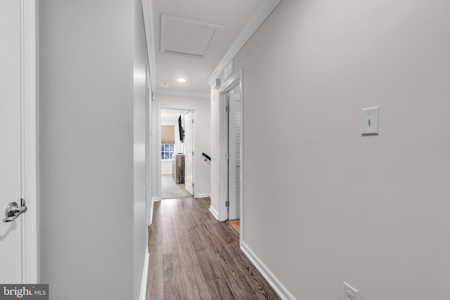 hall featuring attic access, baseboards, ornamental molding, wood finished floors, and recessed lighting