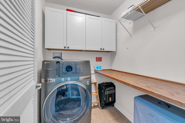 washroom with light tile patterned floors, washer / clothes dryer, cabinet space, and baseboards