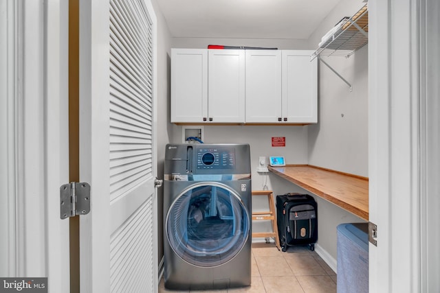 laundry area featuring washer / dryer, light tile patterned floors, and cabinet space