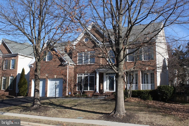 view of front facade with aphalt driveway, a garage, brick siding, and a front lawn