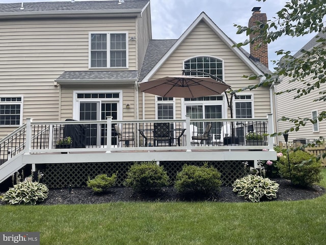 back of property featuring a shingled roof and a wooden deck