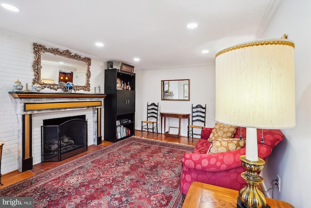 living area featuring recessed lighting, wood finished floors, a fireplace, and crown molding