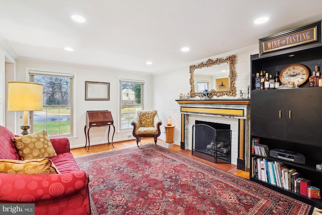 living room featuring recessed lighting, a fireplace, crown molding, and wood finished floors