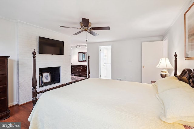 bedroom with dark wood-type flooring, ornamental molding, a fireplace, ensuite bath, and a ceiling fan