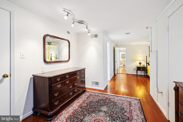 hallway featuring visible vents, baseboards, wood finished floors, and ornamental molding