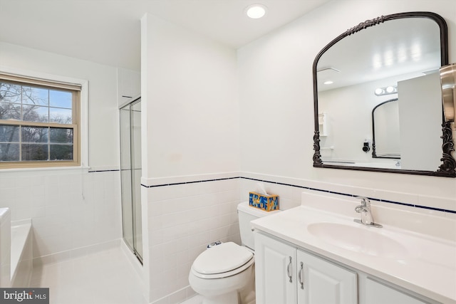 bathroom featuring toilet, a stall shower, tile walls, and vanity