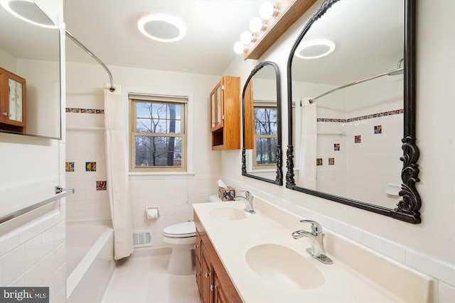 bathroom featuring a sink, visible vents, tile walls, and shower / tub combo