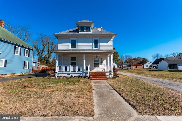 traditional style home with a shingled roof, a front yard, and covered porch