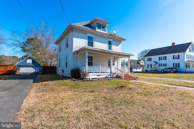 traditional style home with a garage, covered porch, a front yard, and an outbuilding