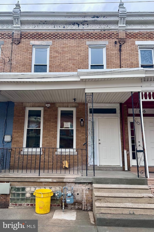 view of exterior entry with covered porch and brick siding