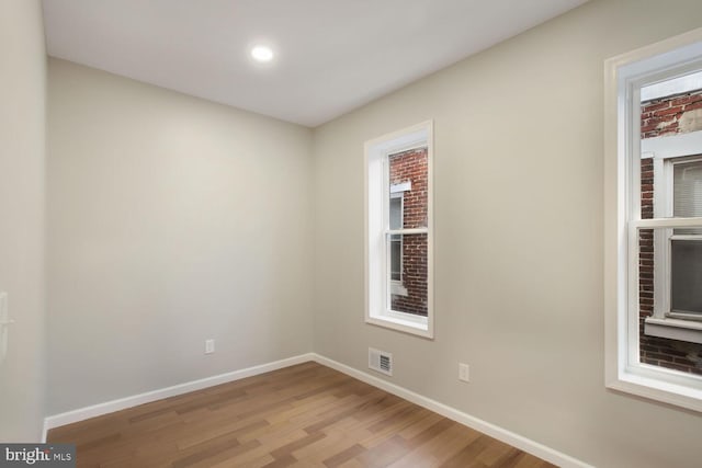 empty room with baseboards, visible vents, and wood finished floors