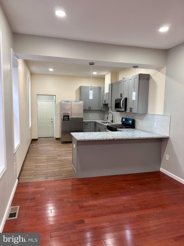 kitchen featuring visible vents, gray cabinetry, appliances with stainless steel finishes, wood finished floors, and a peninsula