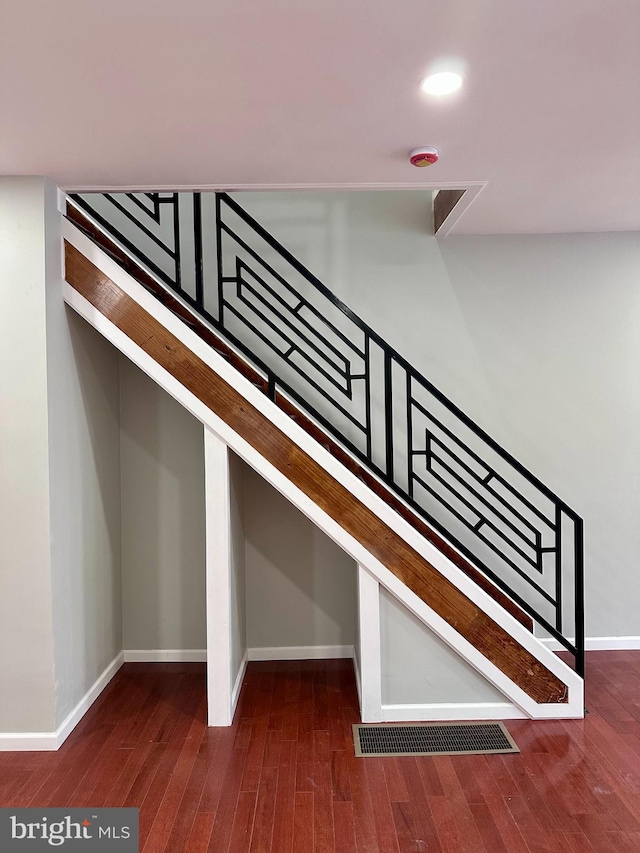 stairway with wood-type flooring, visible vents, and baseboards