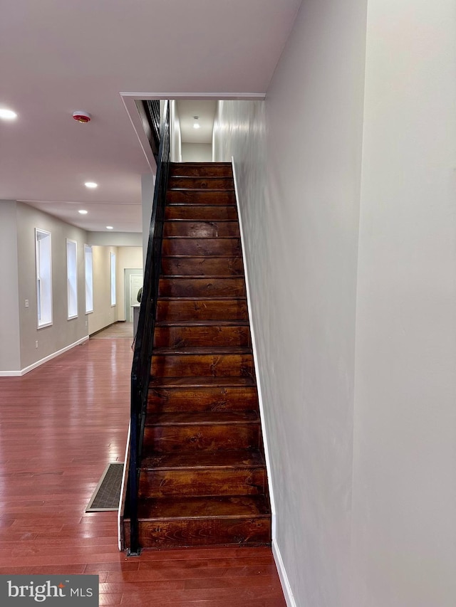 staircase featuring baseboards, visible vents, wood finished floors, and recessed lighting