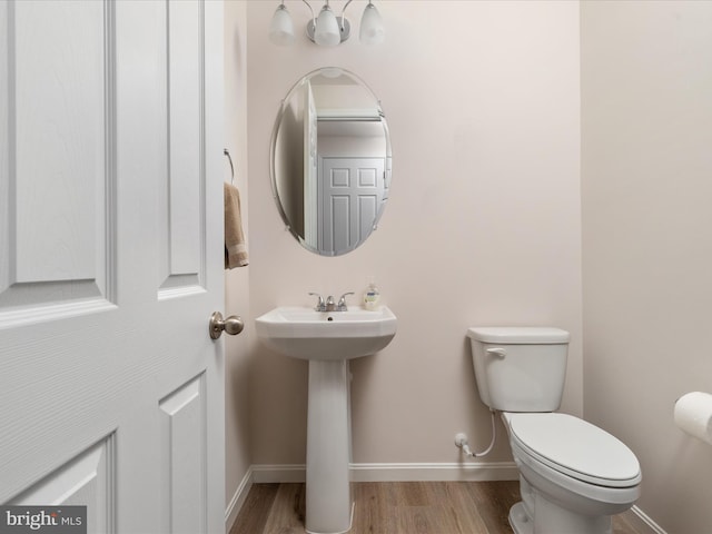 bathroom with toilet, a sink, baseboards, and wood finished floors