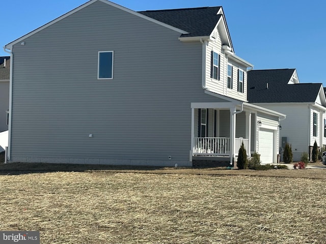 view of home's exterior with covered porch, a yard, and an attached garage