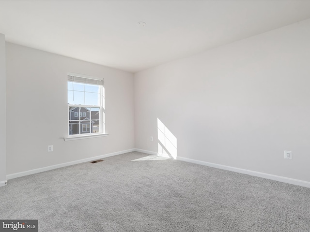 empty room featuring carpet floors, visible vents, and baseboards