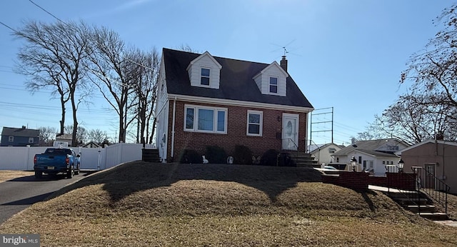 cape cod house with brick siding, a chimney, fence, and a residential view