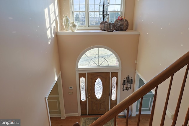 foyer entrance with stairway, wood finished floors, and a towering ceiling