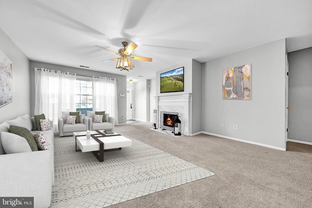 living room with ceiling fan, light colored carpet, a fireplace, visible vents, and baseboards