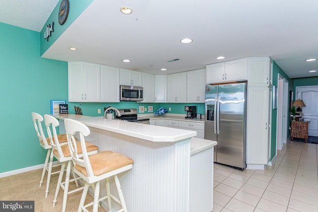 kitchen featuring visible vents, a peninsula, stainless steel appliances, white cabinetry, and recessed lighting