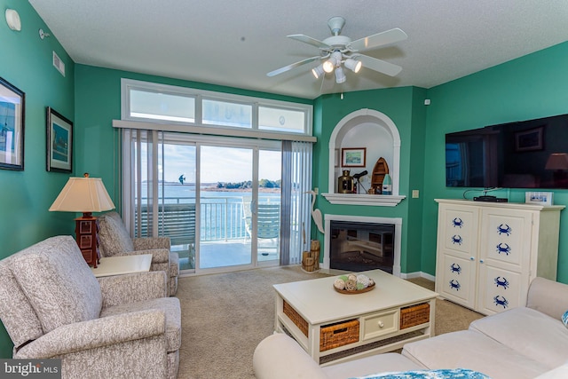 carpeted living room featuring ceiling fan, visible vents, and a glass covered fireplace