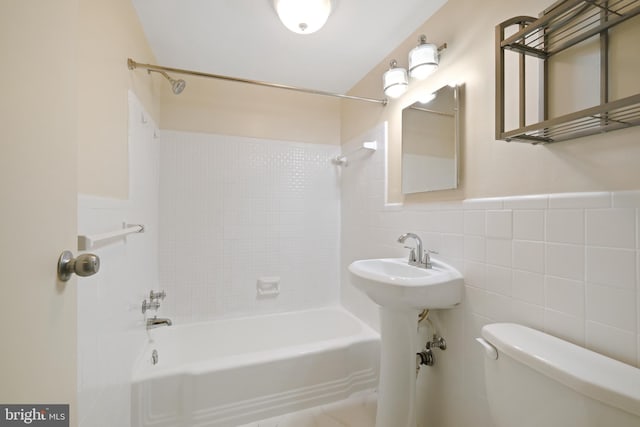 bathroom with toilet, a wainscoted wall, washtub / shower combination, and tile walls