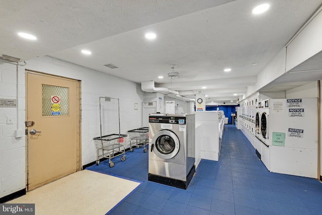 shared laundry area with concrete block wall, recessed lighting, visible vents, and stacked washer and clothes dryer