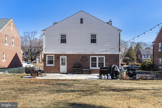 back of house with fence private yard, a patio area, a lawn, and brick siding